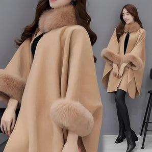 Luxurious women's camel wool cape with faux fur trim, showcasing elegant outerwear style, worn by a model with styled hair and fashionable shoes, highlighting winter fashion.