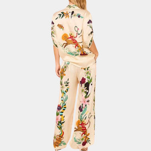 Luxury designer floral silk pajamas featuring elegant embroidery, showcasing long sleeves, a comfortable collar, and a relaxed fit around the waist and thighs. The pajamas highlight exquisite fashion design, suitable for loungewear, with a stylish T-shirt-like top and matching pants.