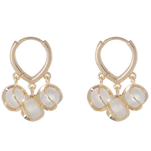 Luxury gold hoop earrings with clear gemstone accents displayed in a vintage box.