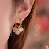Luxury gold hoop earrings with clear gemstone accents displayed in a vintage box.