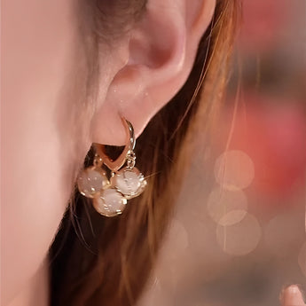 Luxury gold hoop earrings with clear gemstone accents displayed in a vintage box.
