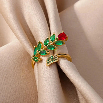 A hand wearing a luxury gold marquise ring with emerald and ruby accents.