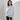 Luxury gray women's cashmere poncho draped elegantly over shoulders, showcasing the soft knit fabric and loose-fitting design. The poncho features a high collar and falls gracefully over the arms, providing a stylish and cozy appearance.