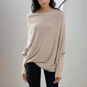 Luxury gray cashmere poncho worn by a woman, showing elegant designer knitwear with a focus on the neck, shoulder, and sleeves. The poncho is styled over a beige outfit, highlighting its versatile and sophisticated design.
