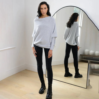 Luxurious gray women's cashmere poncho draped elegantly over shoulders, showcasing a sophisticated fashion design with a soft, flowing silhouette.