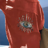 Luxurious green silk blouse featuring sequin eye embellishments, displayed in an orange color variation, size 3XL. The blouse has a stylish neckline and elegant sleeves, reflecting contemporary fashion design.