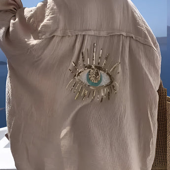 Luxury green silk blouse with sequin eye embellishment, featuring long sleeves and a stylish fashion design.