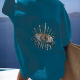Luxury green silk blouse with sequin eye embellishment featuring long sleeves, a rounded neckline, and tailored shoulder design.