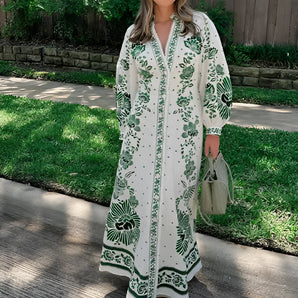 Luxury green and white embroidered maxi coat with floral design, worn by a model standing outdoors on grass, paired with stylish sunglasses and shoes.