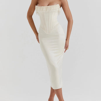 Luxury ivory bridal gown with intricate embroidery and a beaded corset, featuring a flowing one-piece design. The gown highlights the shoulders and neck, complementing the bride's hair and overall elegance.