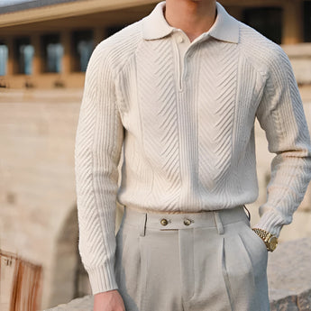 Luxury men's beige knit polo sweater paired with vintage pleated trousers, showcasing elegant outerwear with a collared neckline and long sleeves. The ensemble highlights a sophisticated style with attention to the waist and elbow details.