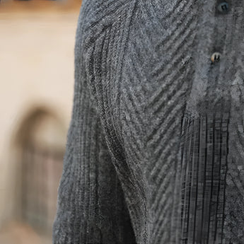 Luxury men's beige knit polo sweater paired with vintage pleated trousers, featuring a textured textile pattern and button accents.
