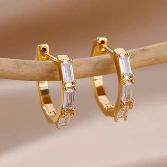Luxury white gemstone gold hoop earrings for women displayed against a plain background, showcasing their intricate design and high-quality materials.