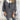 Elegant women's winter fashion coat displayed on a mannequin, showcasing a luxurious white wool cape with gray accents. The garment features a sophisticated design with long sleeves, a high neck, and a tailored waist, emphasizing a chic and stylish appearance suitable for cold weather.