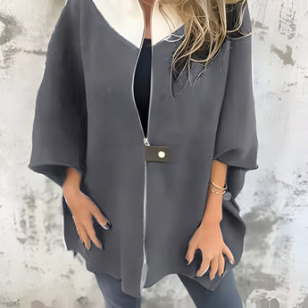 Elegant women's winter fashion coat displayed on a mannequin, showcasing a luxurious white wool cape with gray accents. The garment features a sophisticated design with long sleeves, a high neck, and a tailored waist, emphasizing a chic and stylish appearance suitable for cold weather.