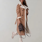 Luxury women's black leather coat with shearling lining displayed on a mannequin, showcasing the long sleeves, structured shoulders, and elegant trench coat design.