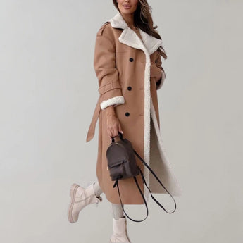 Luxury women's black leather coat with shearling lining displayed on a mannequin, showcasing the long sleeves, structured shoulders, and elegant trench coat design.