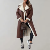 Luxury women's black leather coat featuring a shearling lining, extending to knee length with a classic trench coat style and a fur-lined collar. The coat showcases a sleek design with long sleeves, fitted waist, and thigh-length coverage, perfect for a sophisticated winter look.