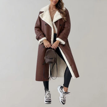 Luxury women's black leather coat featuring a shearling lining, extending to knee length with a classic trench coat style and a fur-lined collar. The coat showcases a sleek design with long sleeves, fitted waist, and thigh-length coverage, perfect for a sophisticated winter look.