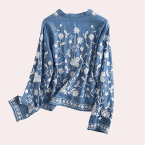Luxurious women's denim top with floral embroidery and bell sleeves, featuring intricate detailing around the neck and sleeve areas, designed for a sophisticated and stylish outerwear look.