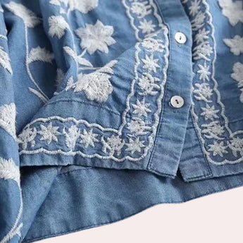 Luxurious women's denim top featuring floral embroidery, bell sleeves, and a button-up collar in an electric blue hue.