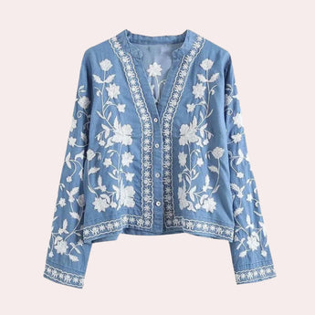 Light blue women's denim top featuring floral embroidery, bell sleeves, and a relaxed fit, displayed on a clothes hanger.