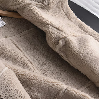 Luxury women's tan suede faux fur winter jacket displayed close-up, highlighting the rich textile texture and soft faux fur lining on the sleeves, against a neutral background.