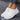 White women's slip-on sneakers with flexible sole, worn by a person; the sneakers are lightweight and breathable, showcased against a grey background.