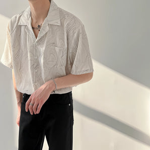 Men's short sleeve shirt with a marble print design in lightweight beige fabric, featuring a collar and casual style, worn by a person demonstrating a relaxed posture.