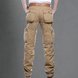 Men's beige cargo pants featuring multiple pockets, displayed on a person, highlighting the pants' utility design and fit on the legs.