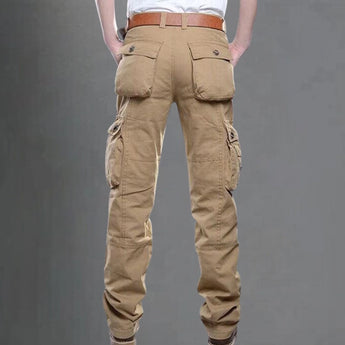 Men's beige cargo pants featuring multiple pockets, displayed on a person, highlighting the pants' utility design and fit on the legs.