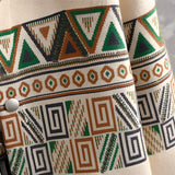 Men's beige sweatshirt featuring a tribal geometric pattern on the sleeves, with a blend of brown and green artistic motifs.