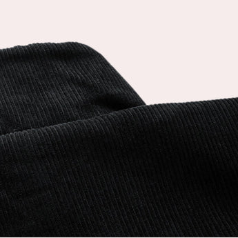 Men's black corduroy bomber jacket featuring ribbed cuffs and a comfortable collar, displayed on a wooden surface.