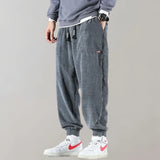 Men wearing light gray corduroy cargo pants with an ankle-tapered fit, paired with a white dress shirt and showcasing urban style.