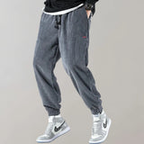 Men's black corduroy cargo pants featuring an ankle-tapered design, suitable for urban style. The pants have visible cargo pockets and a fitted waist, emphasizing both casual and sporty aesthetics.
