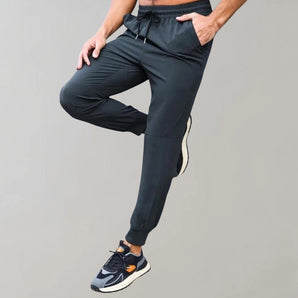 Men's black joggers featuring moisture-wicking fabric, designed with pockets, shown from waist down highlighting the active pants fit on legs and thighs.