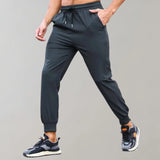 Men's black joggers with moisture-wicking fabric, featuring pockets, worn with sneakers. The pants are styled for athletic activities, showcasing the waist and legs, with a focus on comfort and functionality.