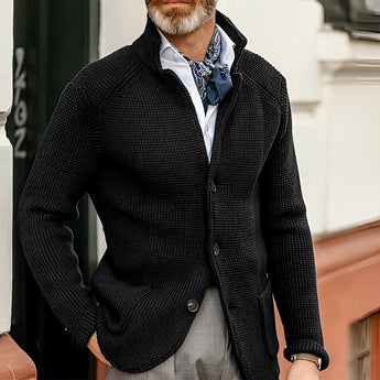 Men's black knit blazer styled as a designer formal cardigan, shown in Nero color and 3XL size. The blazer features a sleek design with a fashion-forward appeal, complemented by a white dress shirt underneath. The image highlights the texture of the knit fabric and the blazer's form-fitting silhouette, including the neckline, sleeves, and waist.