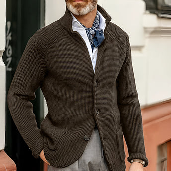 Men's black knit blazer modeled by a bearded man in a formal setting, showcasing the designer cardigan style with a focus on fashion and textile detail.