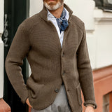 Men's black knit blazer worn by a bearded man over a dress shirt, showcasing sleeve and waist details against a grey backdrop.