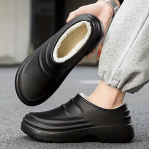 Men's black leather slip-on loafers with a warm fleece lining, designed to be non-slip, featuring a sleek and modern style.