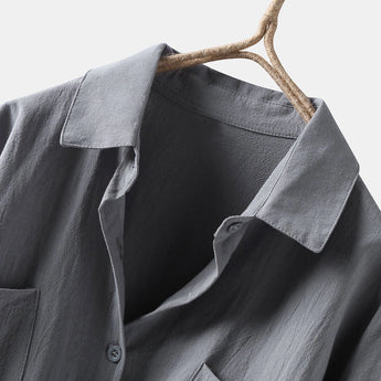 Men's black linen shirt hanging on a hanger, featuring long sleeves and a pointed collar, showcasing its lightweight and breathable fabric ideal for eco-conscious fashion choices. The shirt is displayed against a neutral background, highlighting its versatility and stylish design suitable for both casual and formal occasions.