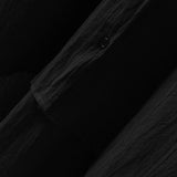 Men's black linen shirt displayed on a wooden table with a grey and wooden pattern.