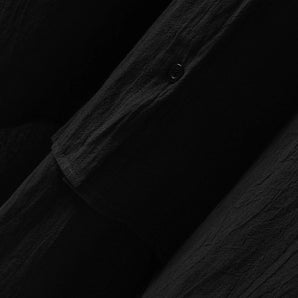 Men's black linen shirt displayed on a wooden table with a grey and wooden pattern.