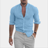 Men wearing a light blue slim fit casual shirt with a textured V-neck and rolled sleeves, showcasing the shirt's design while standing with a slight gesture; the model has a beard and is wearing a watch.
