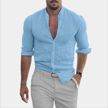 Men wearing a light blue slim fit casual shirt with a textured V-neck and rolled sleeves, showcasing the shirt's design while standing with a slight gesture; the model has a beard and is wearing a watch.
