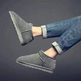 Men's black slip-on winter boots with fleece lining displayed on a person, paired with jeans, highlighting their non-slip and durable features.