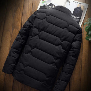 Men's black thermal water-resistant puffer jacket displayed in an indoor setting with tire elements around, highlighting its rugged and durable nature.