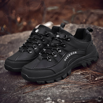 Men's black waterproof hiking shoes with non-slip soles, featuring a lightweight design suitable for outdoor trails, displayed outdoors on grass with trees in the background.