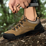 Men's beige waterproof hiking shoes shown on a person walking outdoors in a natural setting with grass and trees, highlighting the footwear's lightweight and non-slip features suitable for trail activities.